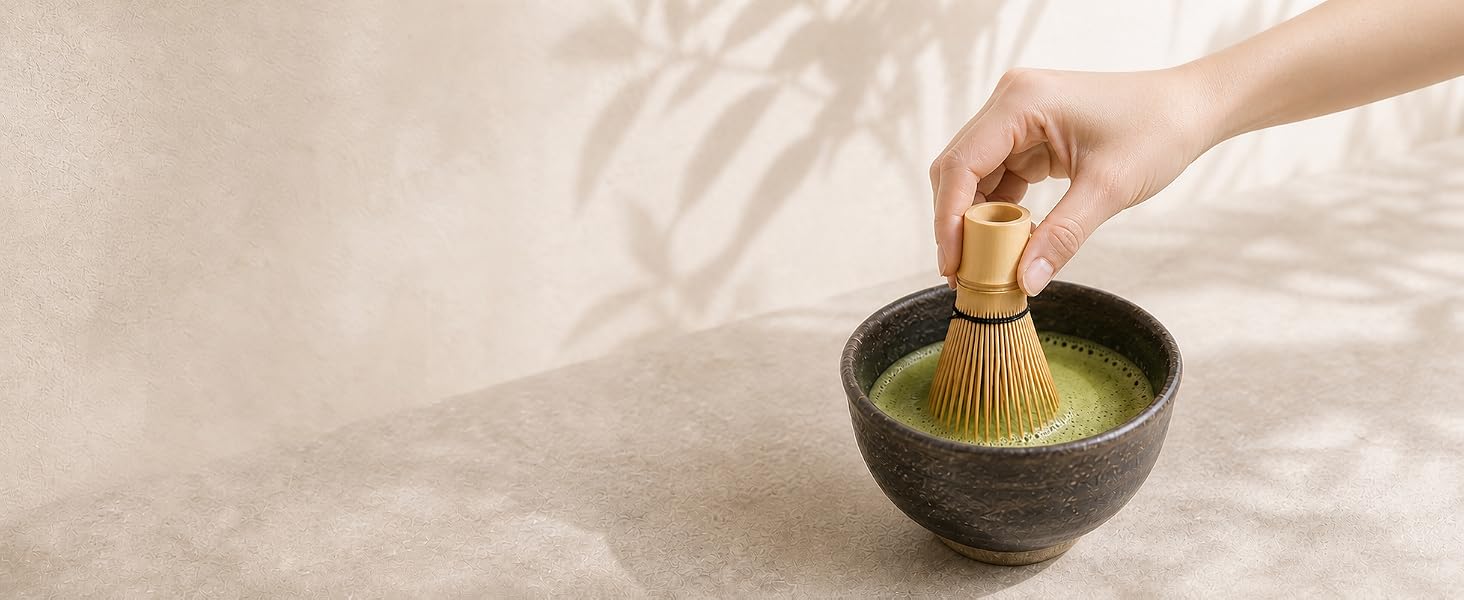 A hand whisking bright green OSARI matcha in a bowl